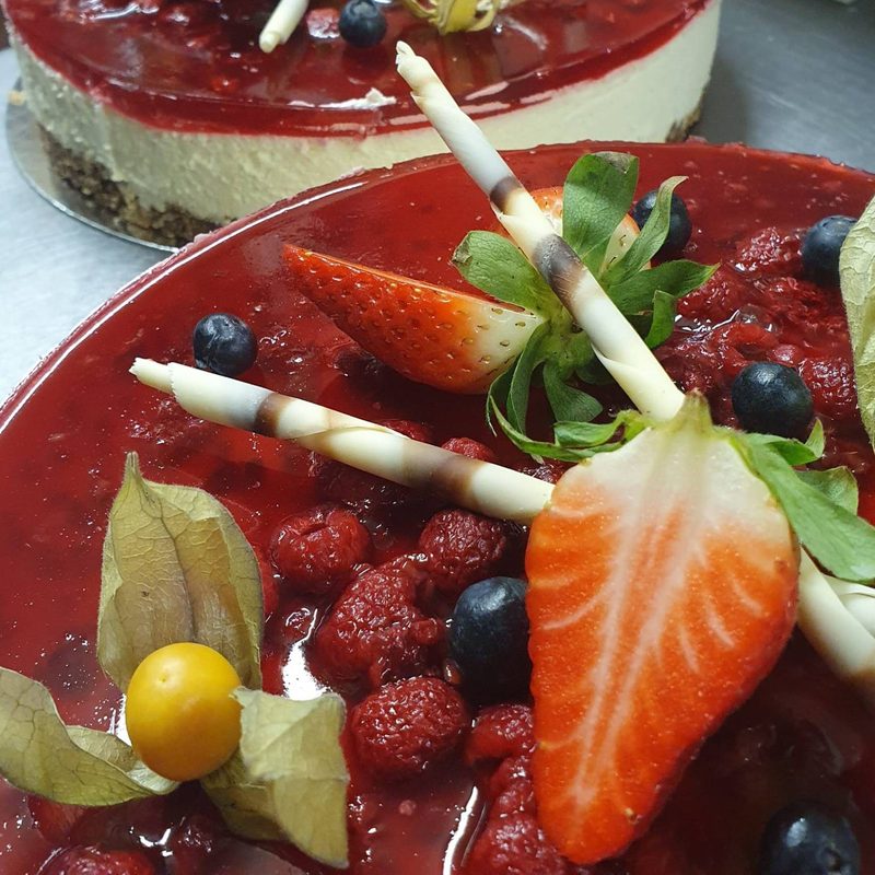 A berry-glazed cheesecake with strawberries and white chocolate curls