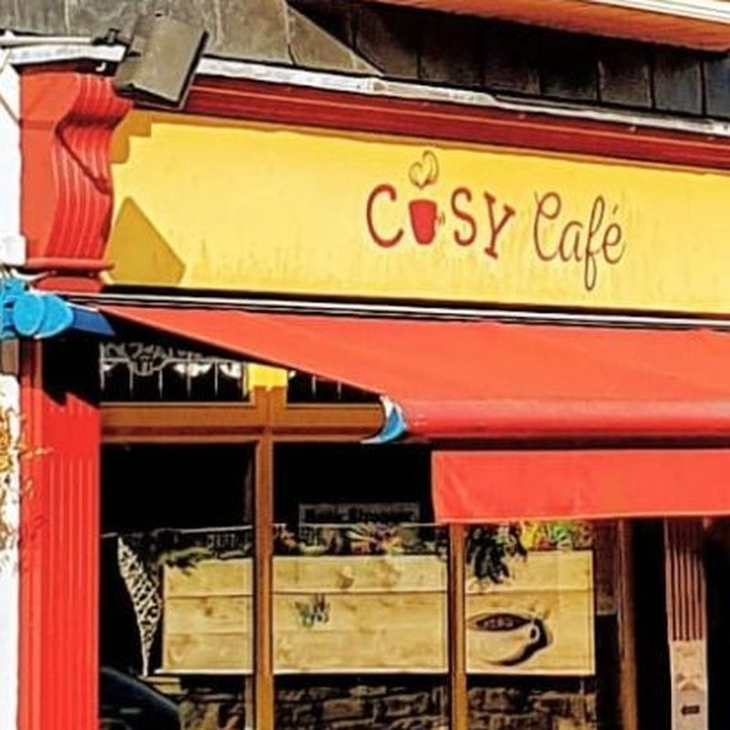 The yellow Cosy Café sign and red awning on Church Square