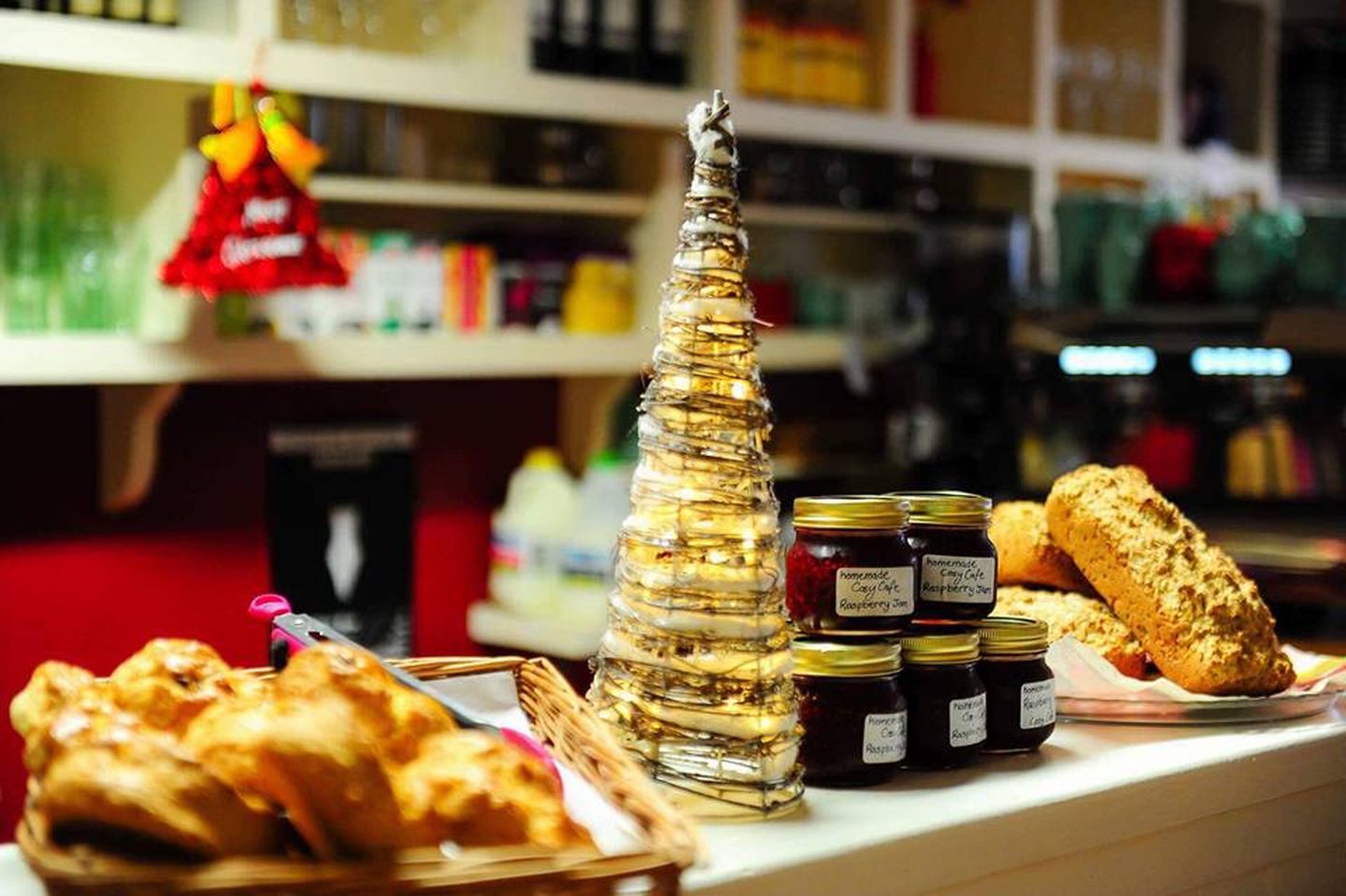 The Cosy Café counter with a basket of croissants, jars of homemade raspberry jam, soda bread and a small tree of fairy lights